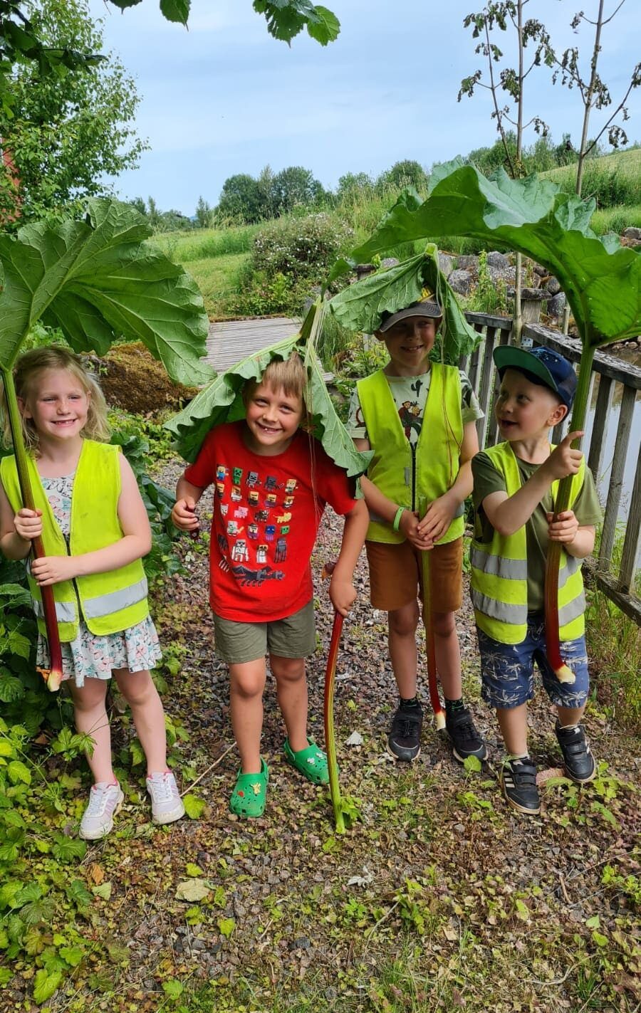 Barn som leker med rabarberblad i en trädgård